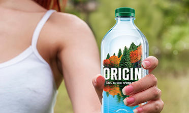 A woman holding an Origin Water bottle and wearing a white tank top.